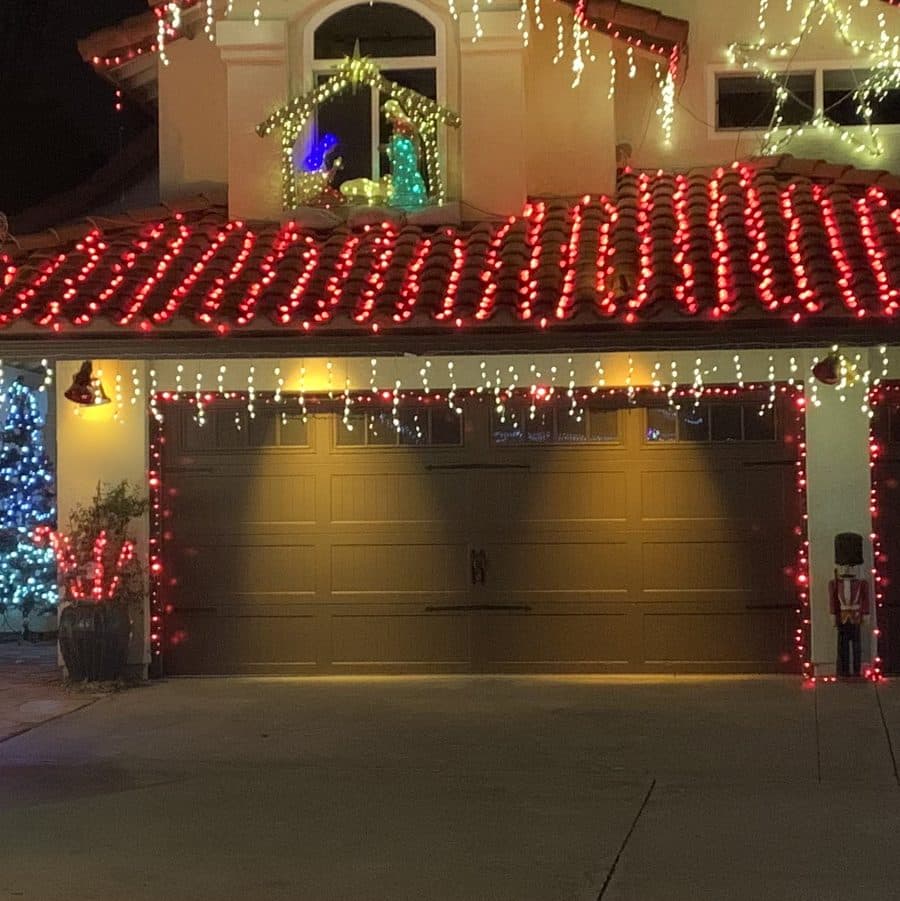 Warm white icicle lights hanging from the eaves over a two-car garage, with red bulbs outlining the garage doors.
